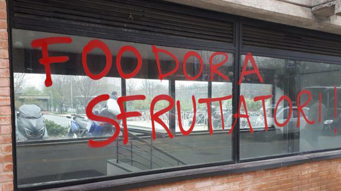 “Foodora sfruttatori” – La scritta al PalaGiustizia. Domani riprende la causa dei ‘rider’ licenziati